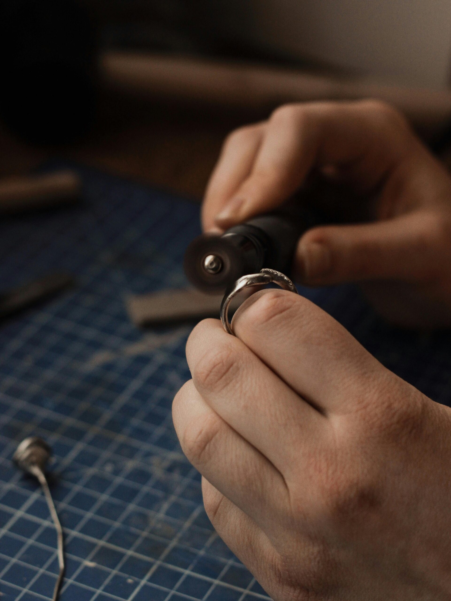 Close-up of a craftsman polishing a silver ring, showcasing intricate metalsmith skills.